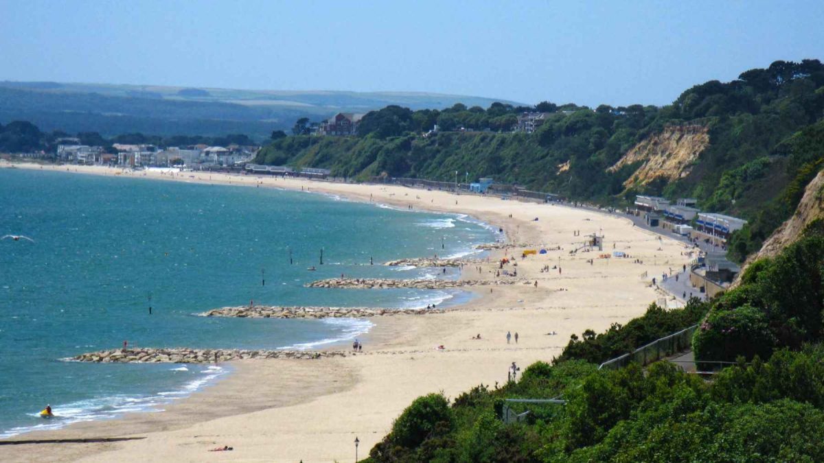 Wide view of Canford Cliffs in Poole Bay, Dorset, showing the sandy beach and the protected clifftop coastline.