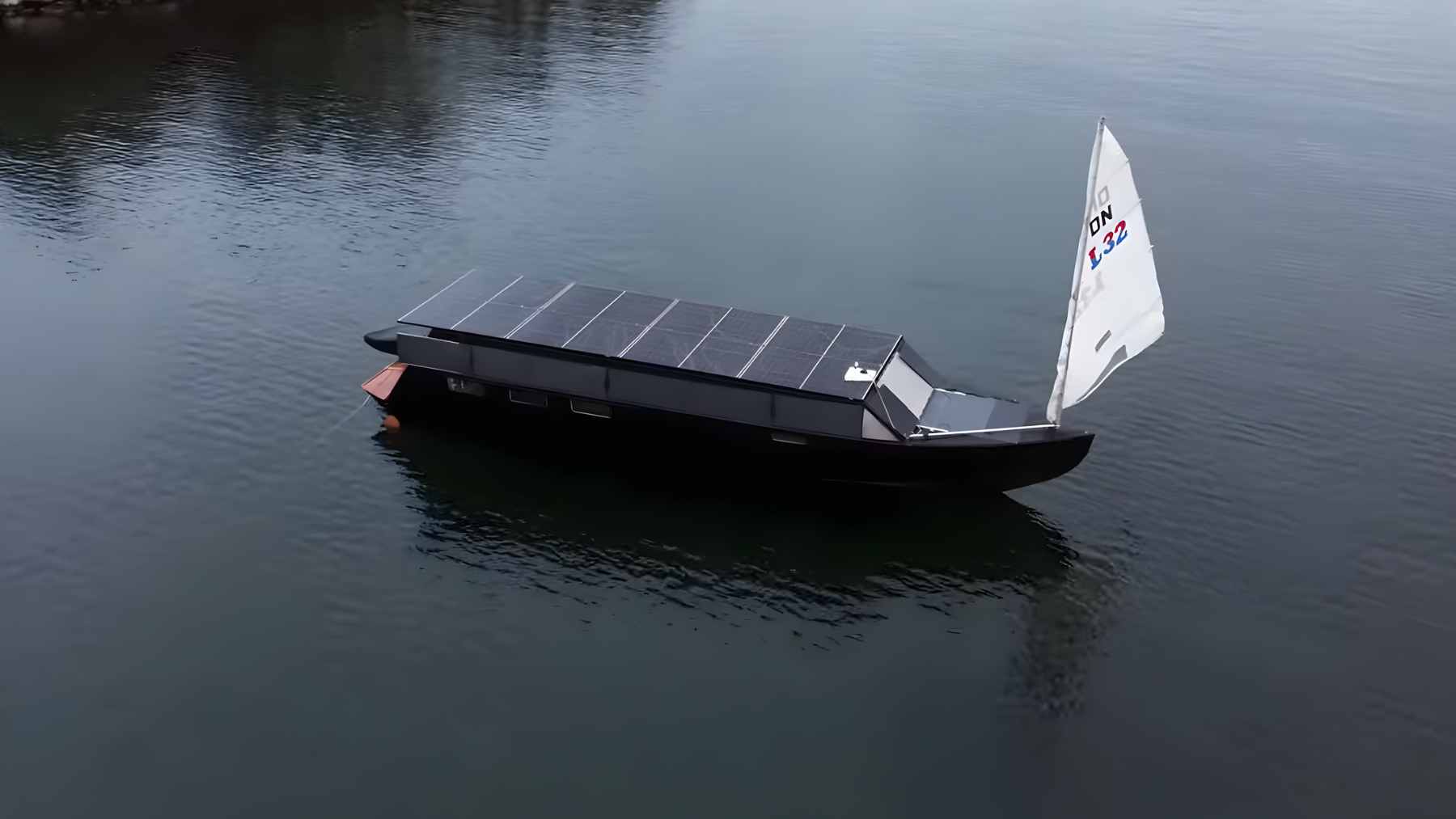 The solar-powered yacht Helios 11 navigating through partially frozen French canals with its integrated roof-mounted solar panels.
