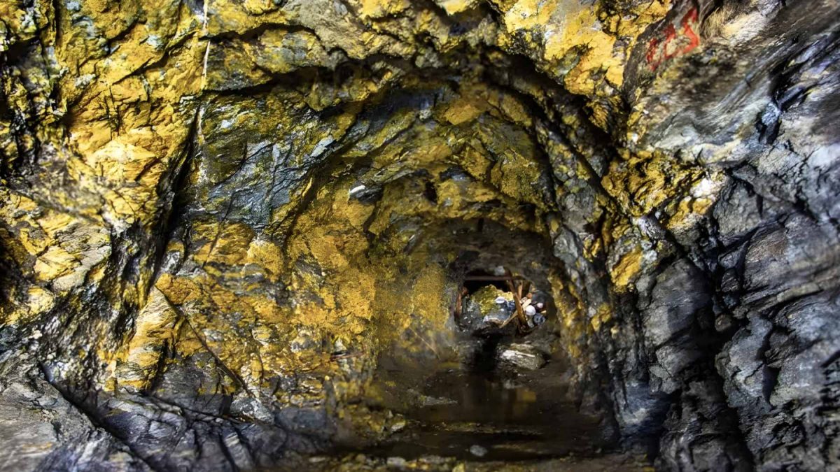 Interior view of the Wangu gold field in Hunan, China, showing golden-hued rock faces within a deep mining tunnel.