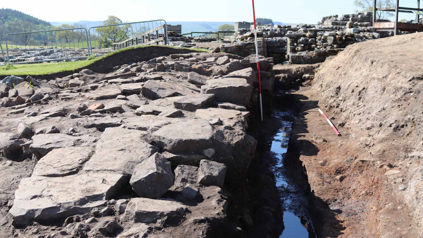 Archaeological remains of a Roman stone sewer drain at Vindolanda fort, used to study ancient intestinal parasites.