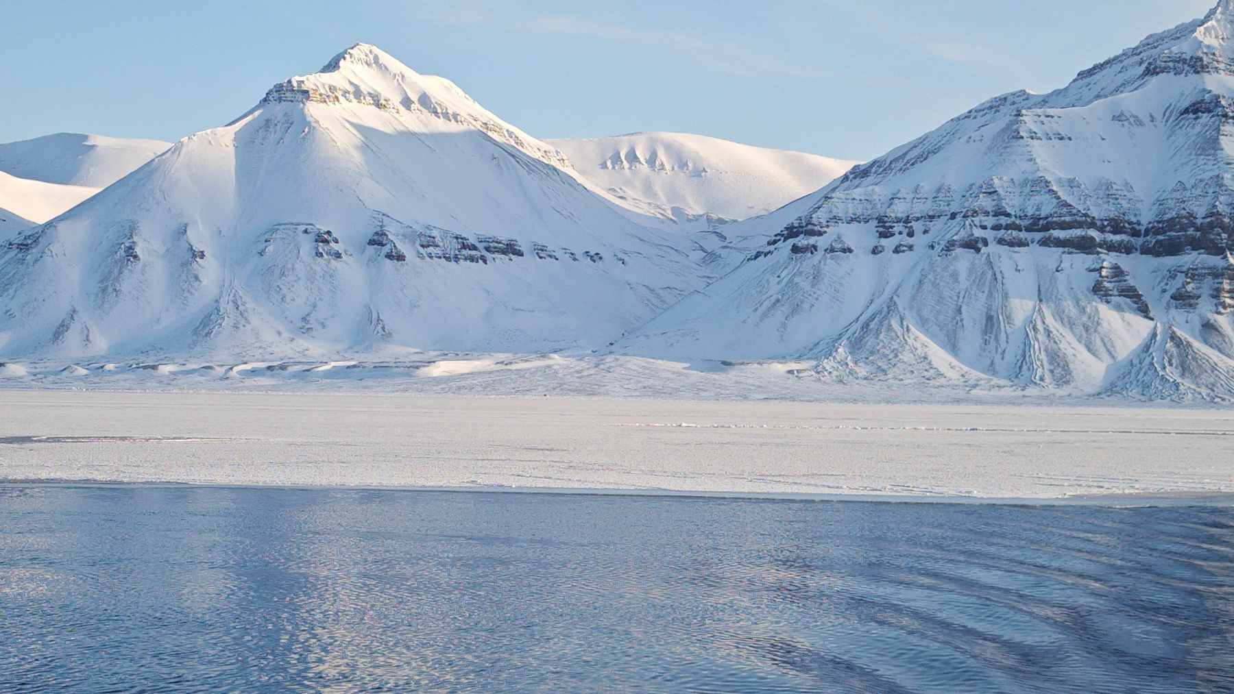 A historical illustration of 17th-century sailors hunting reindeer and building a makeshift brick shelter on the icy shores of Spitsbergen.
