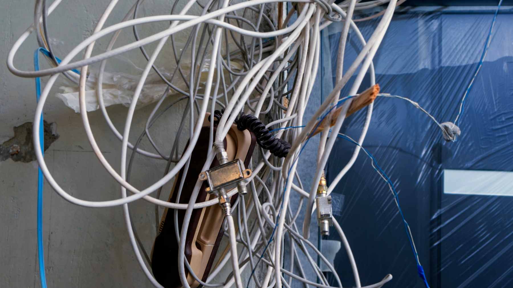 A G.hn bridge adapter showing an ethernet port (RJ45) and a telephone port (RJ11) connected to vintage copper telephone wiring.