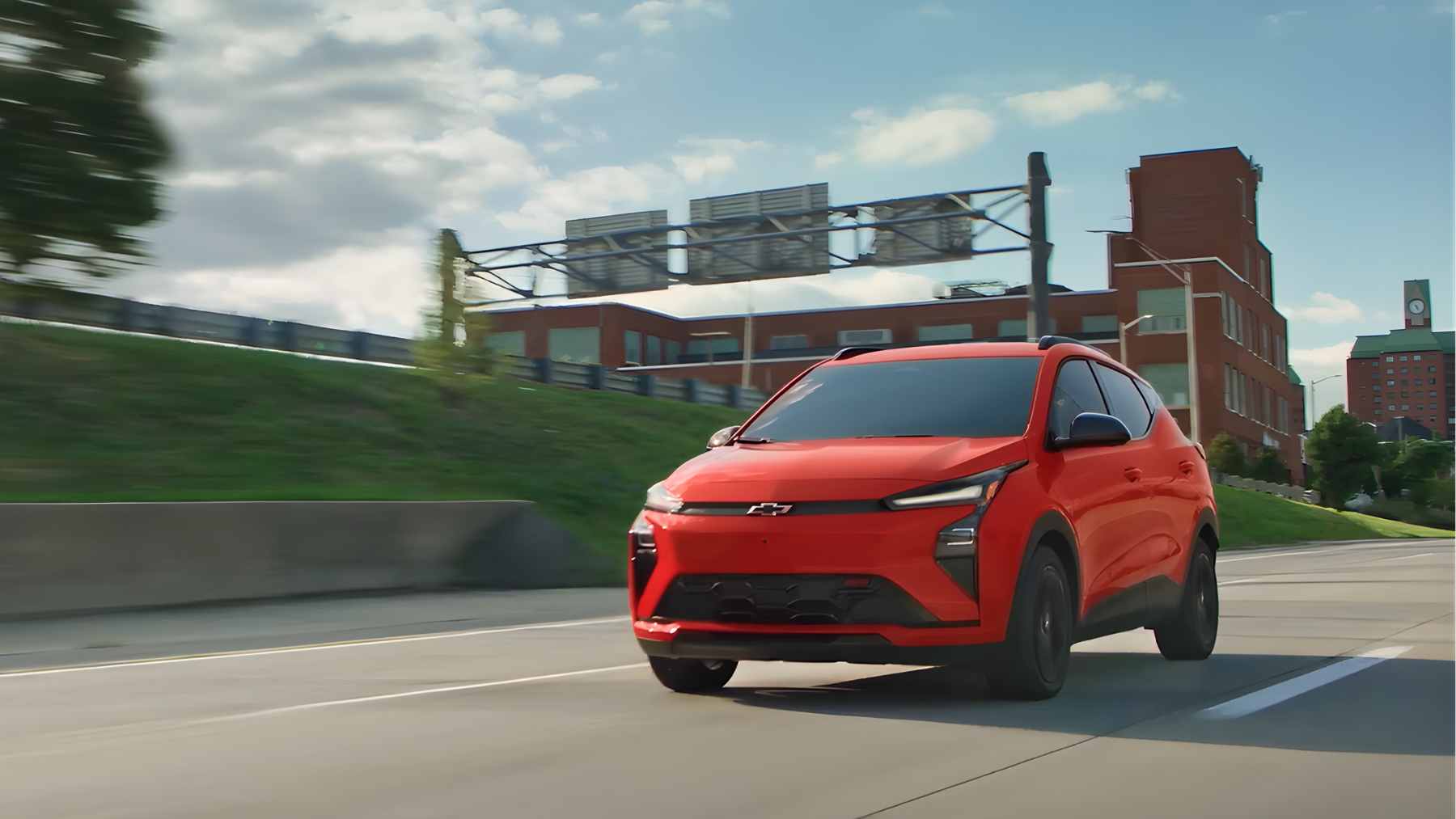 A white Chevrolet Bolt EV parked in a garage, plugged into a wall-mounted home charging station.