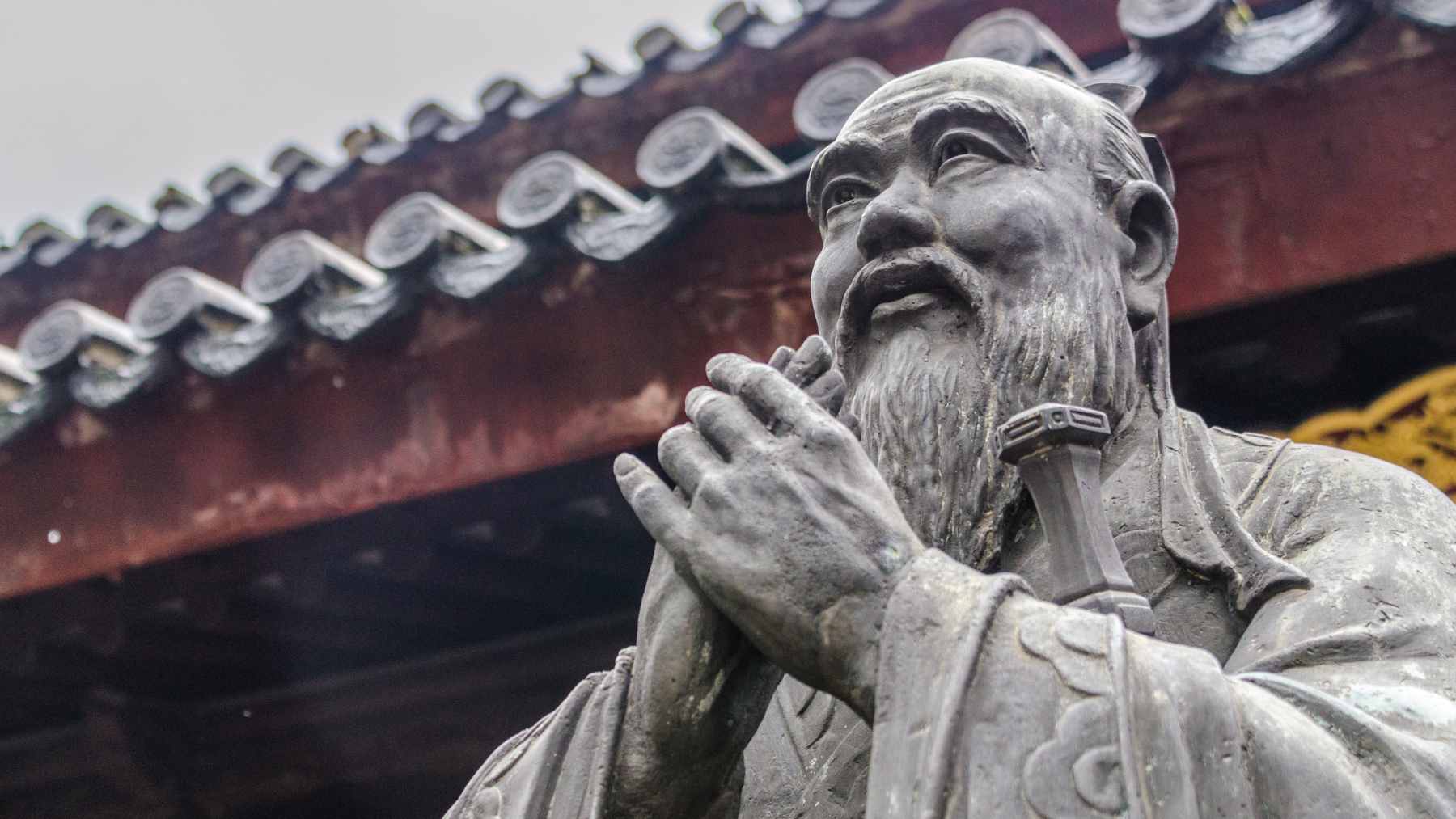 A conceptual illustration of the Confucian proverb "The man who moves a mountain begins by carrying away small stones," showing a path built from small rocks.