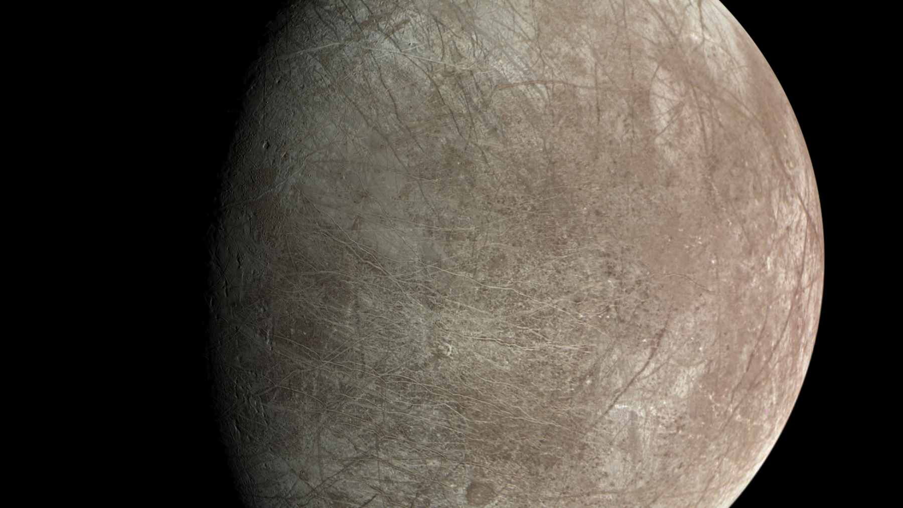 A cross-section diagram of Jupiter's moon Europa showing the thick outer ice shell, the global liquid ocean, and the rigid rocky seafloor mantle.