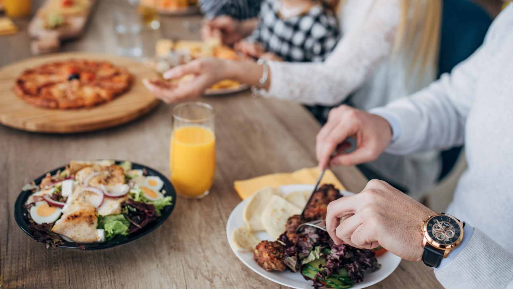 A family preparing a healthy home-cooked meal together in a kitchen with fresh vegetables and chicken.