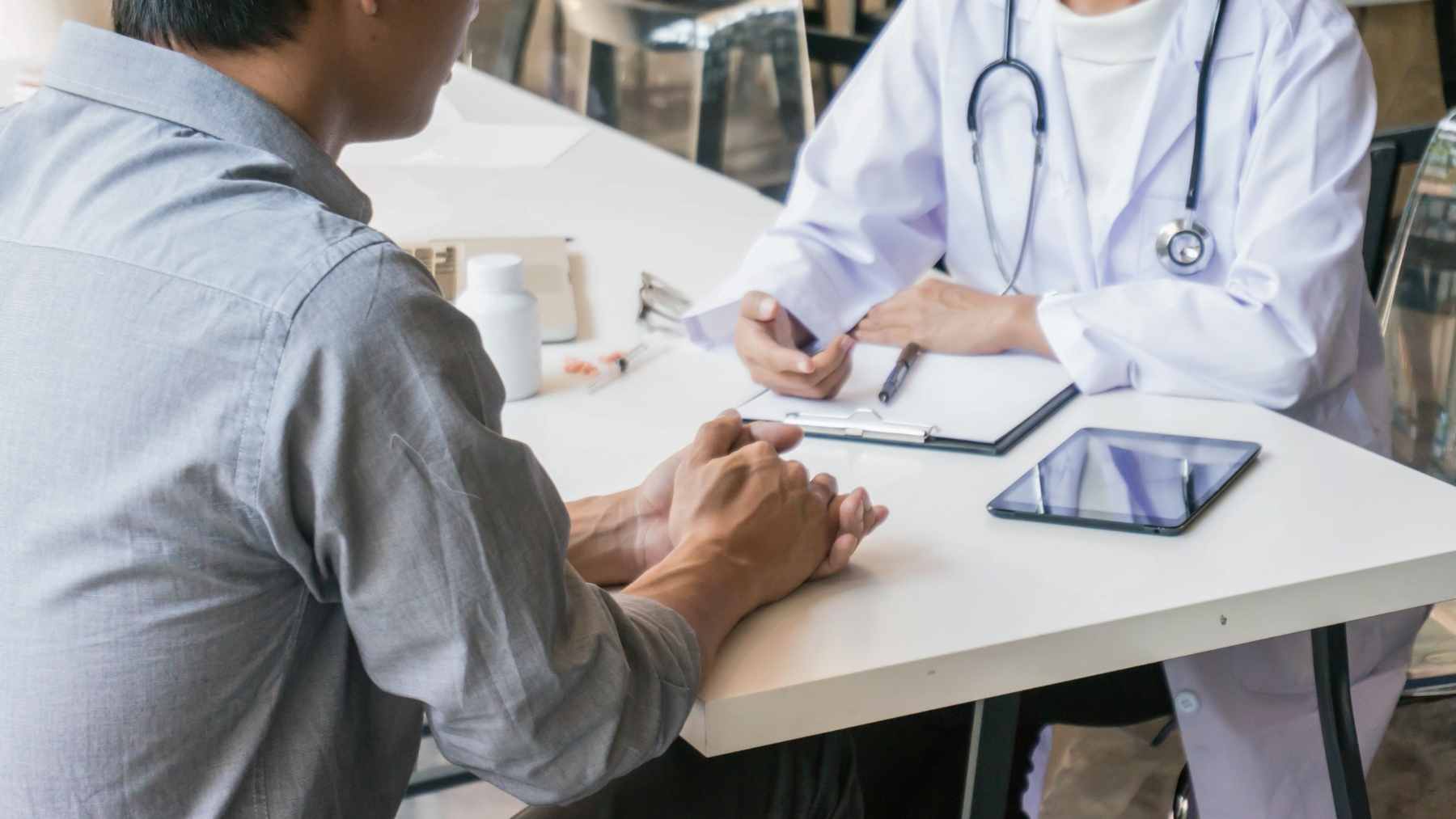 A scientific researcher examining a glass of milk and a cut of raw beef in a laboratory setting.