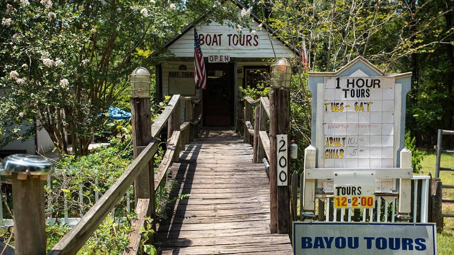 A scenic view of a coastal cliff overlooking a sandy beach with the Pacific Ocean and distant mountains in the background.