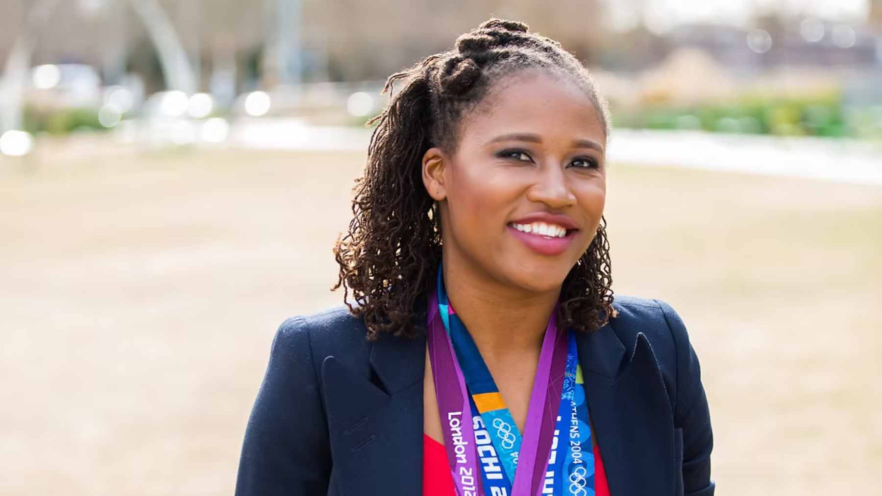 Portrait of Olympian Lauryn Williams smiling and wearing multiple medals from the London 2012 and Sochi 2014 Olympic Games.
