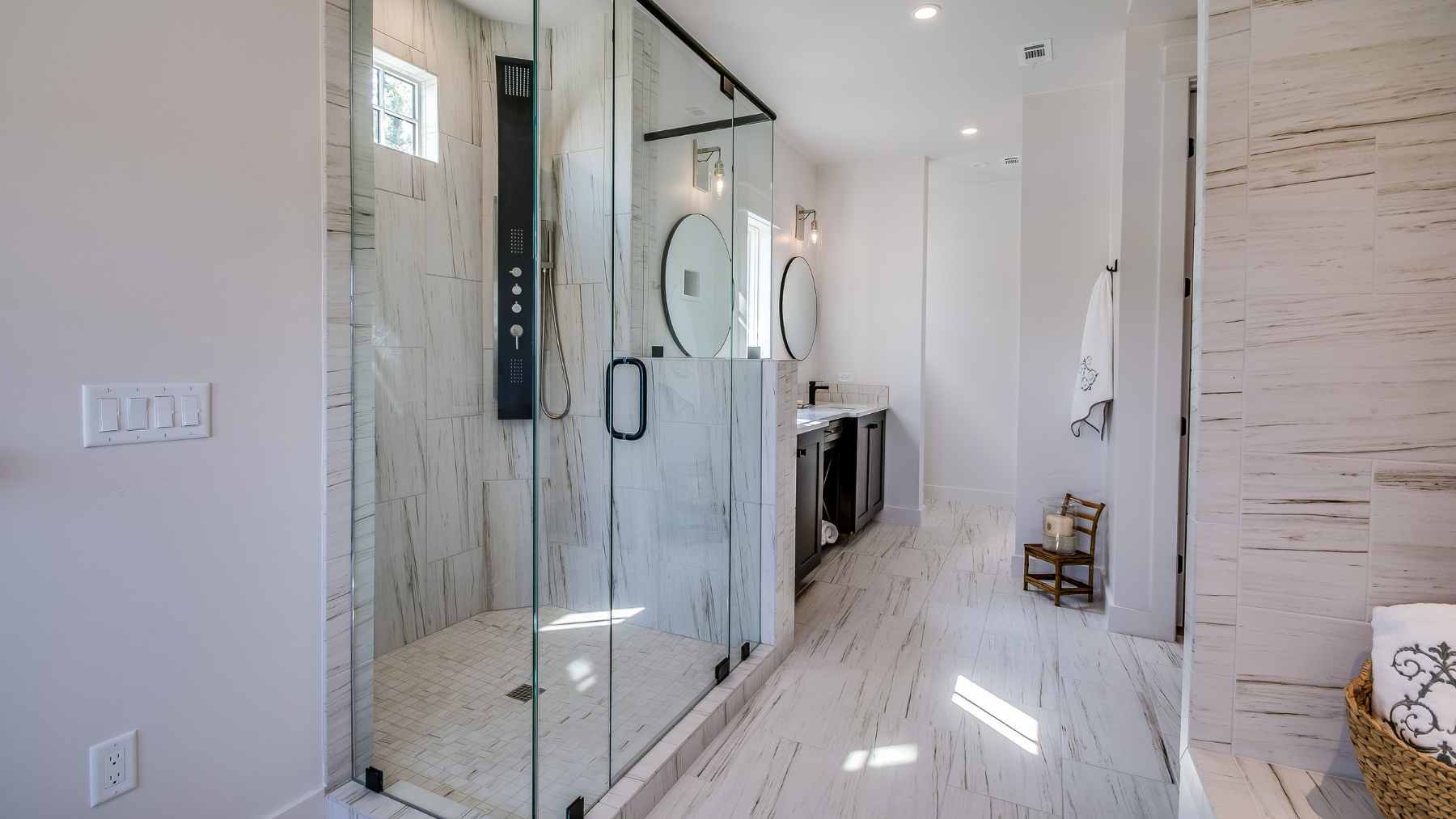 A modern, small bathroom featuring a clear, frameless fixed glass shower panel and light-colored tiling to maximize space.