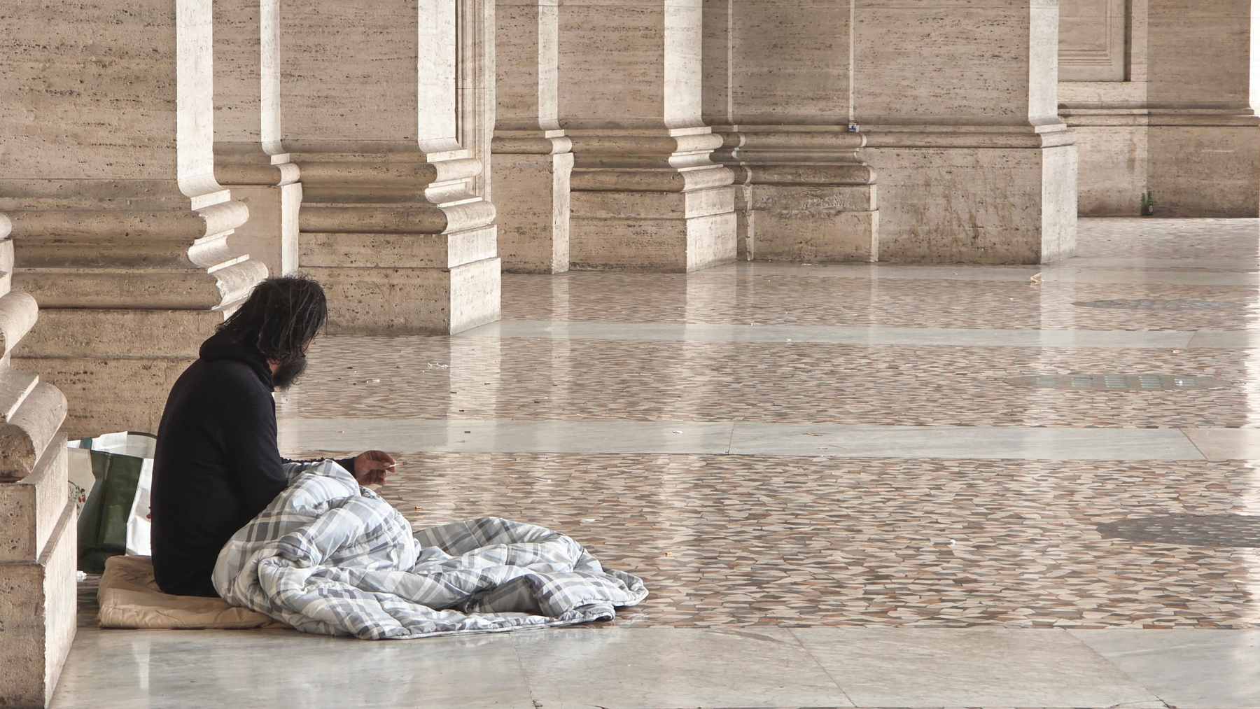 A street outreach worker in New York City speaking with an unsheltered individual near a subway entrance.