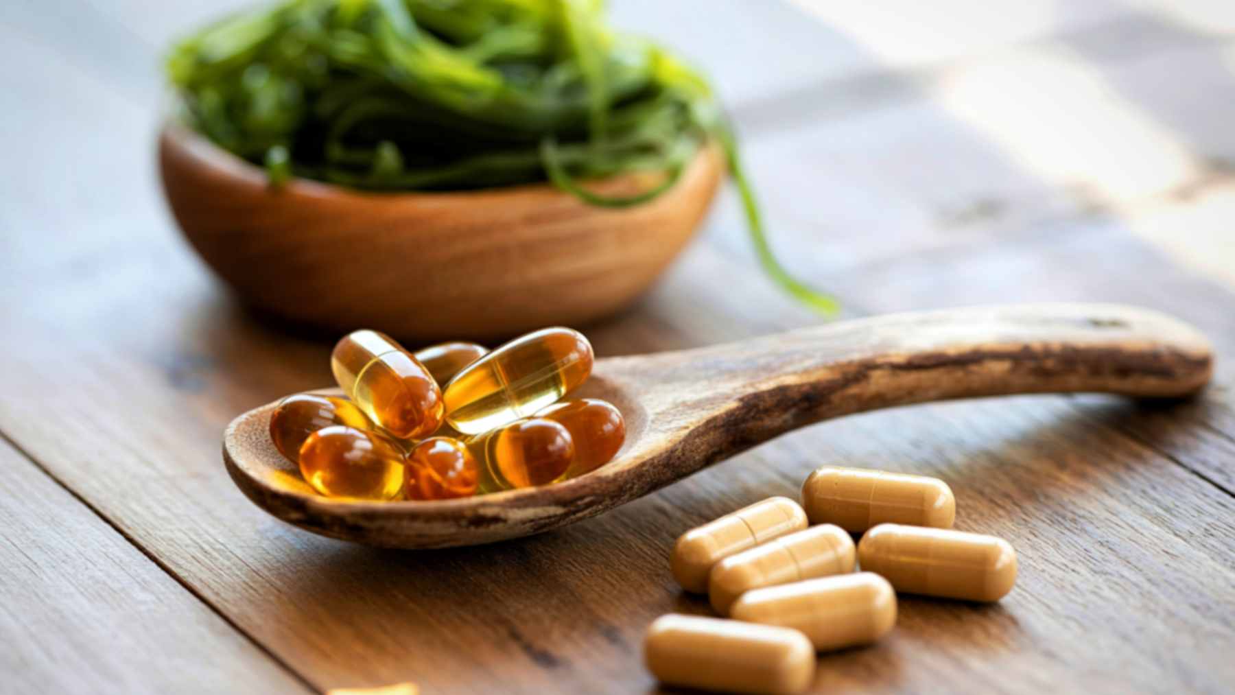 A close-up of amber-colored omega-3 fish oil capsules on a white surface, representing nutritional supplementation for brain health.