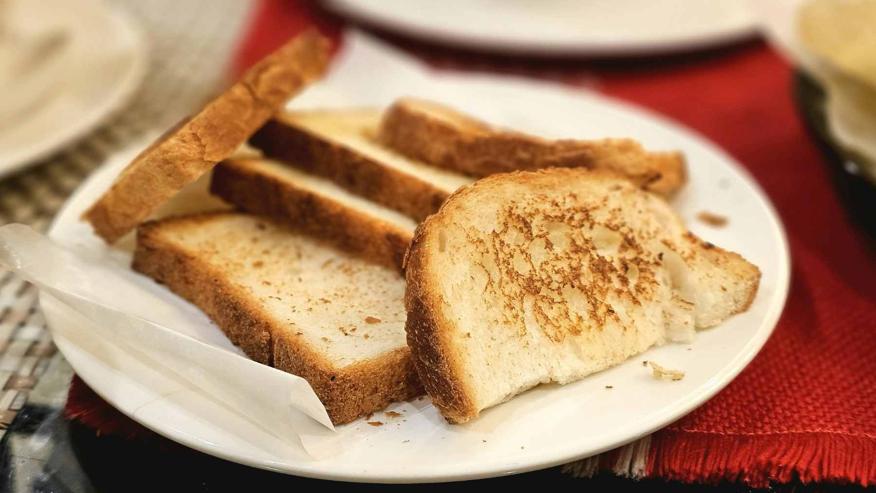 A close-up of a golden-brown, pan-fried slice of bread in a cast-iron skillet, showing a crispy olive oil crust.