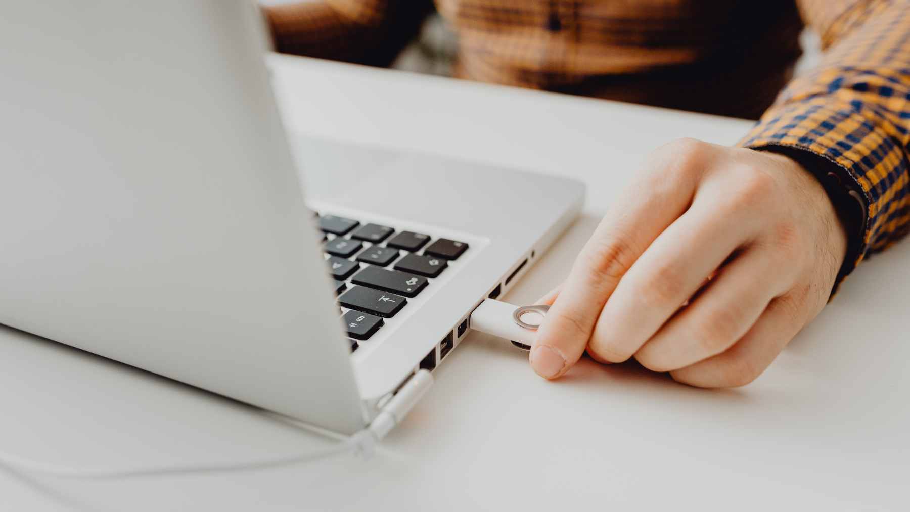 A high-speed portable SSD connected to a modern laptop alongside an older, dusty USB-A flash drive.