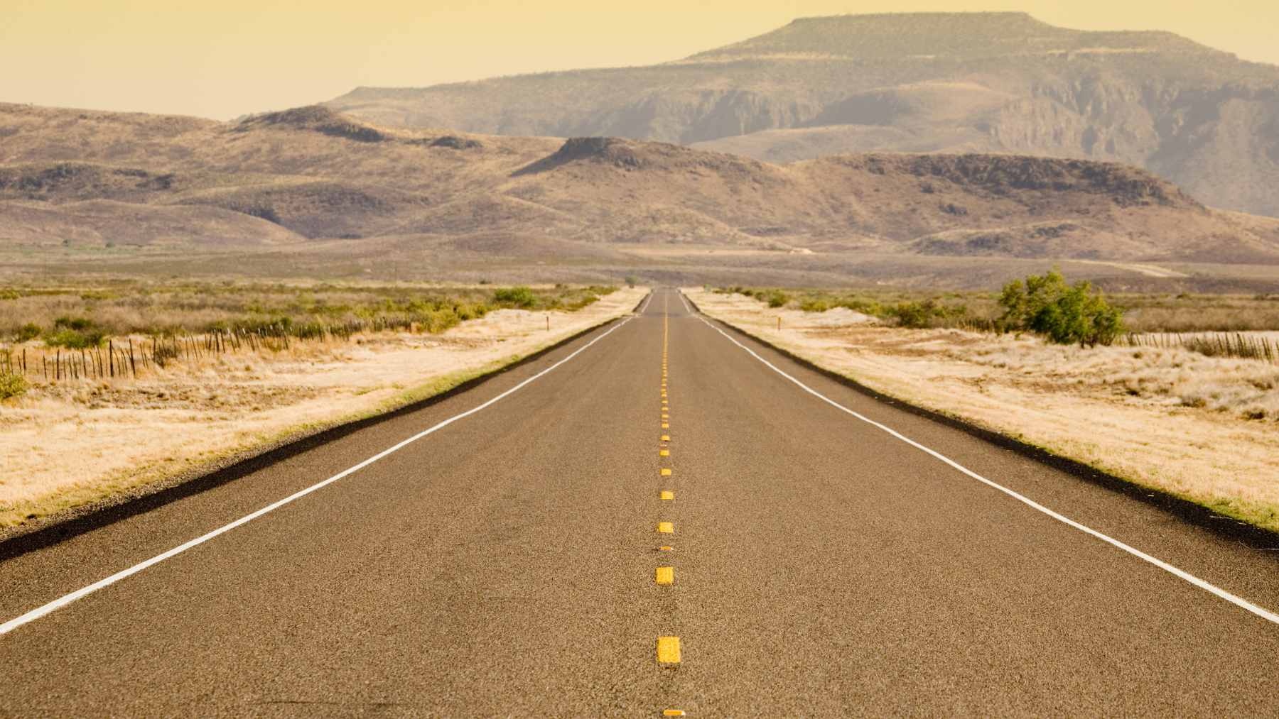An aerial view of Saudi Arabia’s Highway 10, showing a perfectly straight asphalt road stretching to the horizon through the desert.