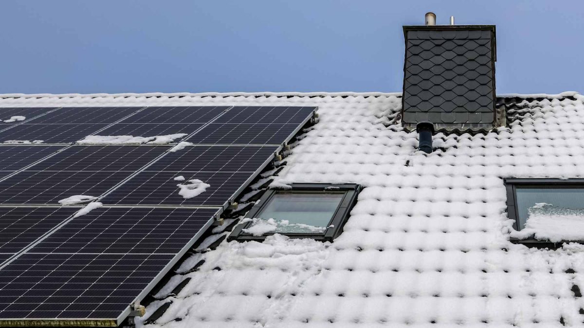 A rooftop solar panel array with a light dusting of snow on a winter day, illustrating winter energy production.
