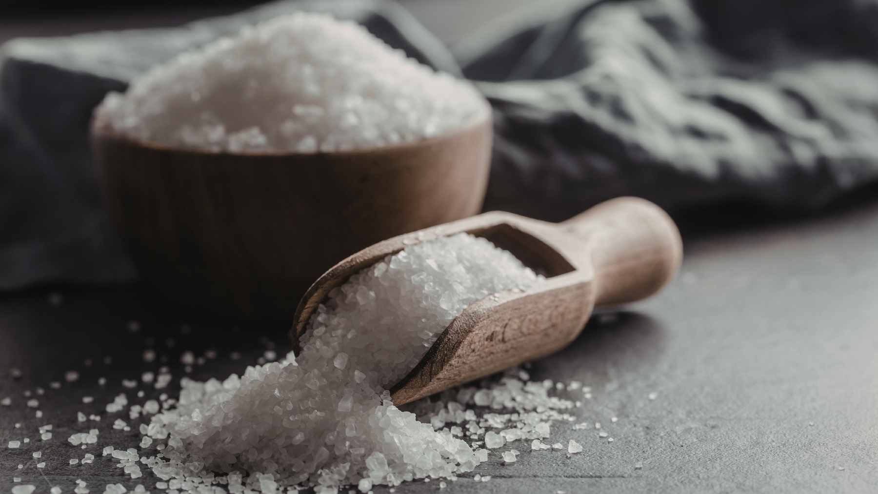 A small white bowl filled with table salt sitting on a white windowsill to absorb window condensation.