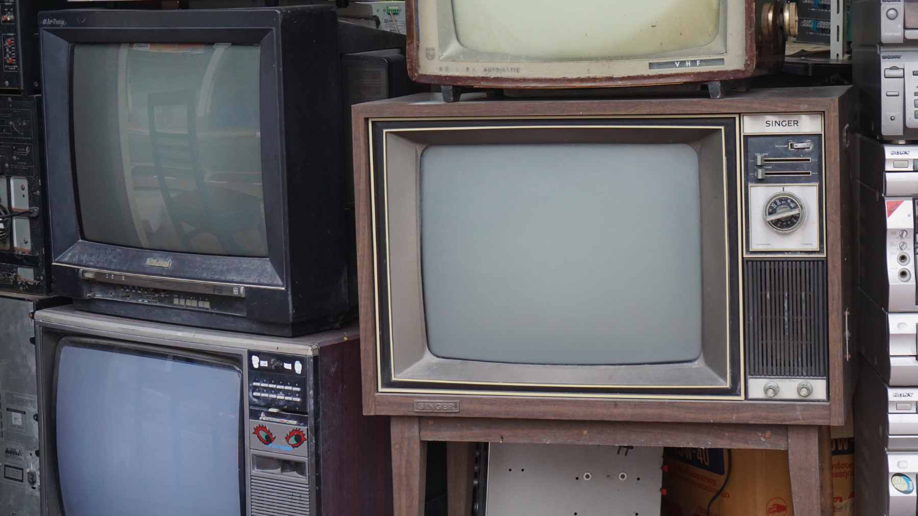 A vintage 1970s television set that has been gutted and repurposed into a cozy, cushioned bed for a small cat.