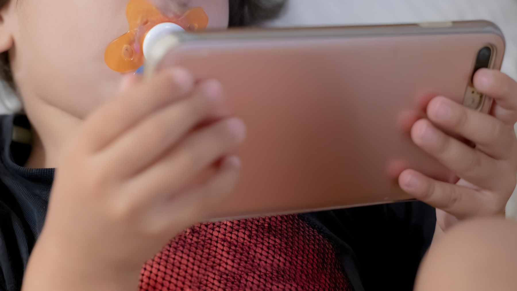 A young child looking at a smartphone screen, illustrating the focus of the Singapore GUSTO brain development study.