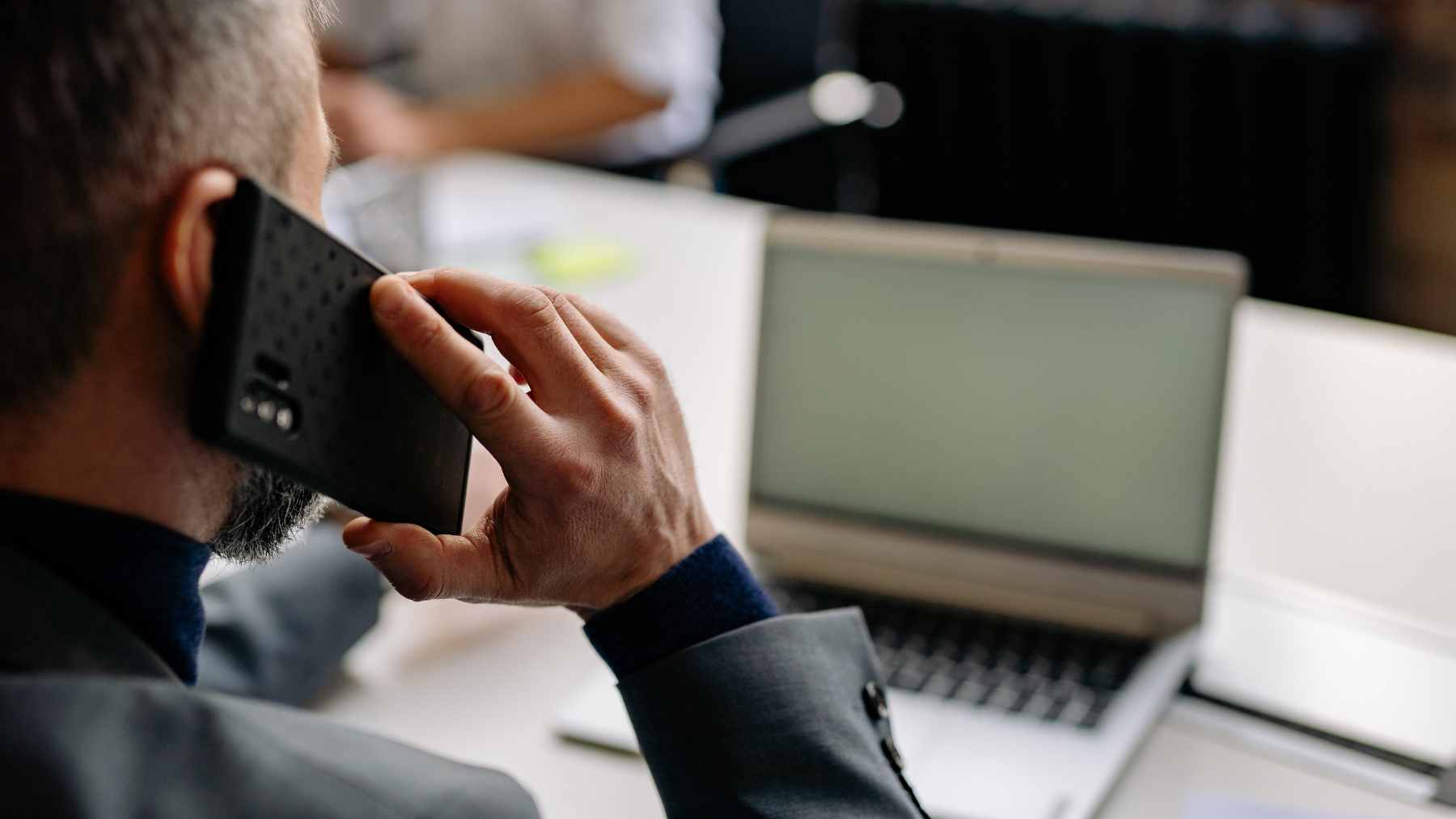 A person looking at a smartphone screen with an unknown number, preparing to answer the call professionally.