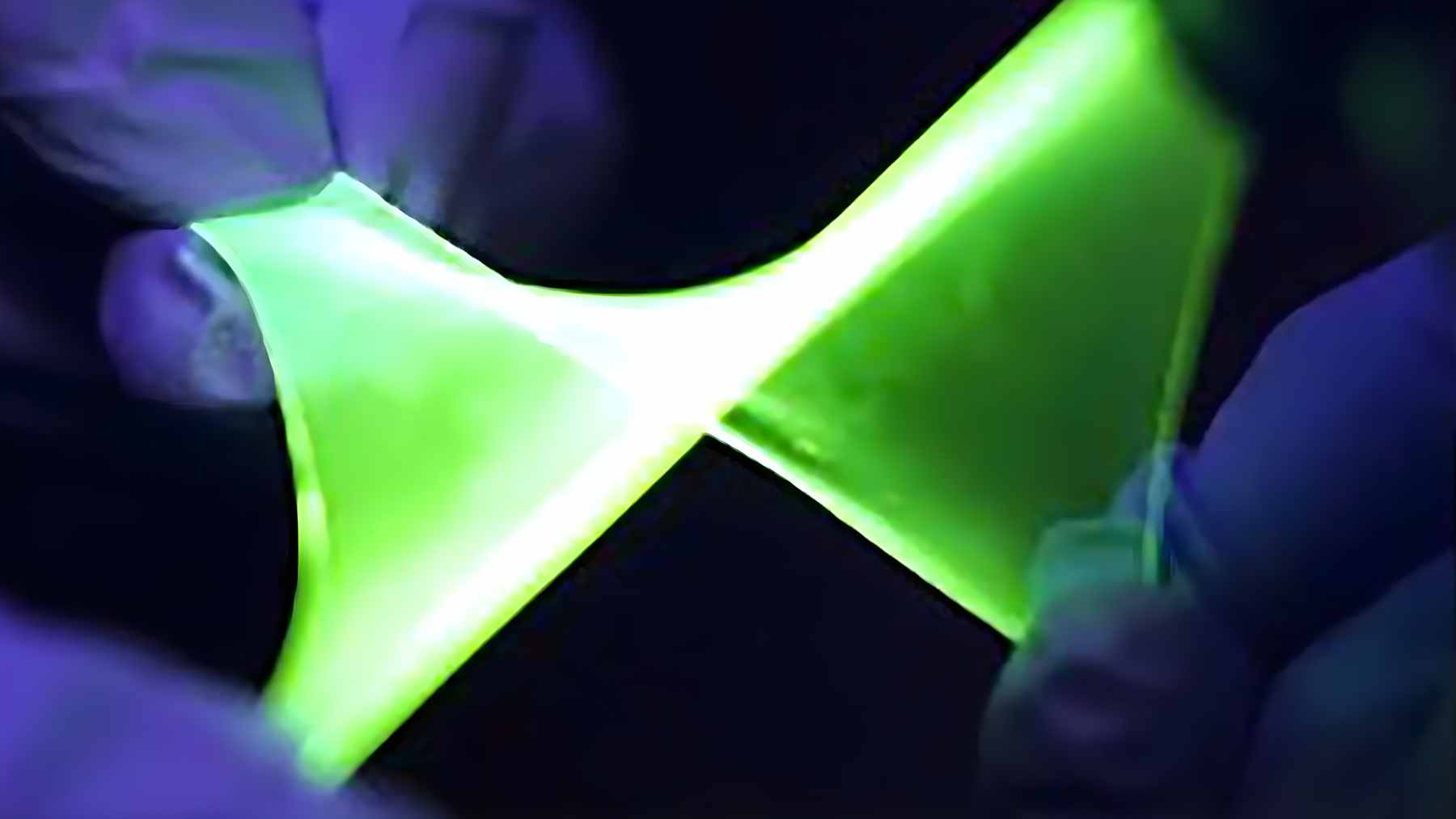 A high-tech stretchable OLED display showing a glowing green heart shape while being mechanically pulled to 60 percent strain.